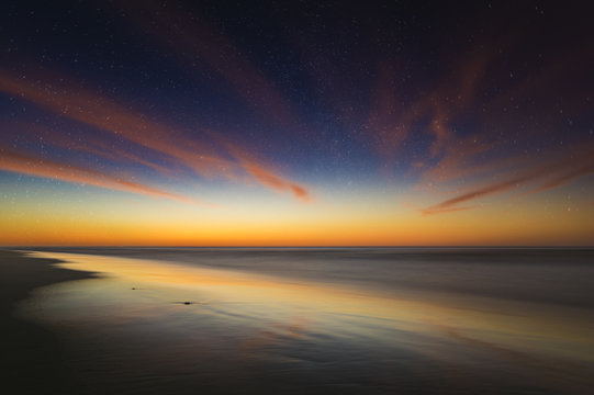 beautiful, evening sky with stars reflecting on a wet ocean beach