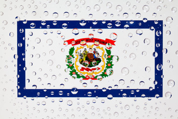 Flag of American State West Virginia behind a glass covered with rain drops.