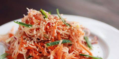 Vegan salad with carrot and radish. Asian cuisine. Healthy vegetarian appetizer on the round plate. Side dish. Simple low calories lunch. Wide photo.