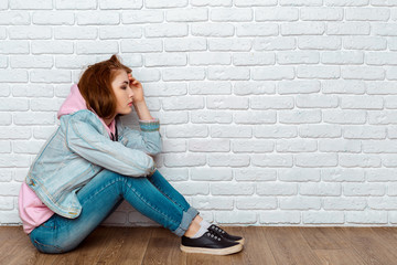 Fototapeta na wymiar Sad woman sitting on floor near wall