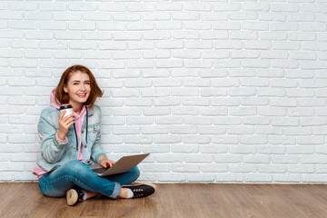 Portrait of a cheerful woman sitting on the floor with laptop