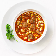 white beans and meat casserole cooked in tomato red wine gravy and decorated with parsley