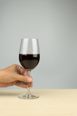 hand putting a glass of red wine on the wooden table