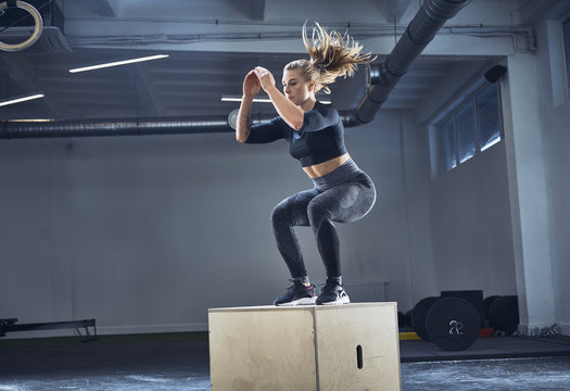 Athletic woman doing box jump exercise at gym