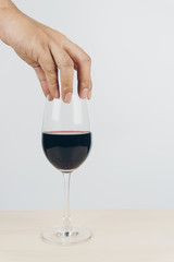 hand putting a glass of red wine on the wooden table