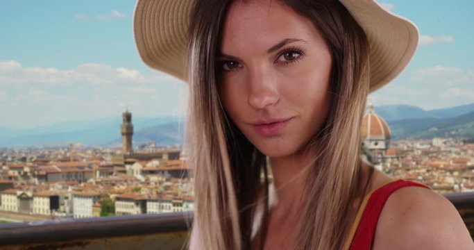 Close-up of stylish hipster girl looking at camera with Florence cityscape in background, Portrait of pretty millennial Caucasian girl in her 20s in Florence, Italy, 4k