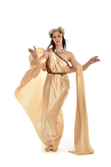 full length portrait of brunette woman wearing long golden grecian gown, standing pose. isolated on white studio background. - obrazy, fototapety, plakaty