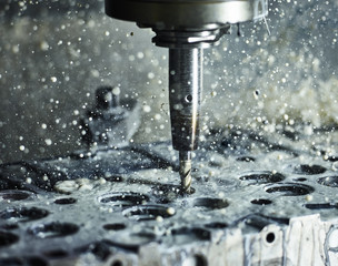 CNC machine drilling into cylinder head with coolant