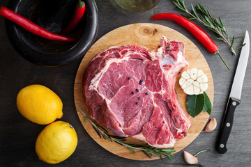 Raw beef fillet steak with herbs and spices on black wooden background