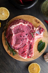 Raw beef fillet steak with herbs and spices on black wooden background