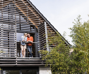 Happy mature couple standing on balcony of their house