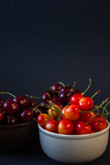 Ripe juicy cherries on a black background. Delicious cherries in plates.