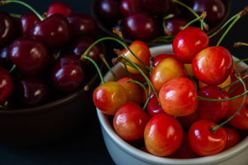 Ripe juicy cherries on a black background. Delicious cherries in plates.