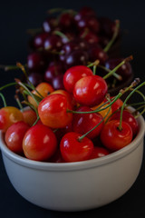 Ripe juicy cherries on a black background. Delicious cherries in plates.
