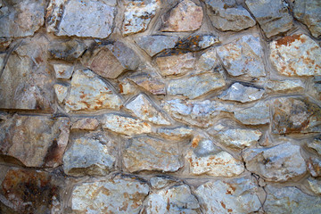 The wall is made of natural stone. Stone wall masonry is a natural material