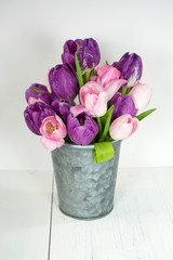 purple and pink tulip bunch in gray metal bucket on whitewashed wood