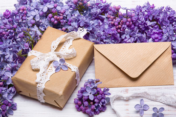 Lilac flowres, gift box and envelope on white wooden background. Retro style. Holiday composition, copy space