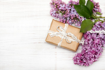 Lilac flowers, gift box on white wooden background, copy space