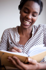 Close up happy black female author at home writing in notebook