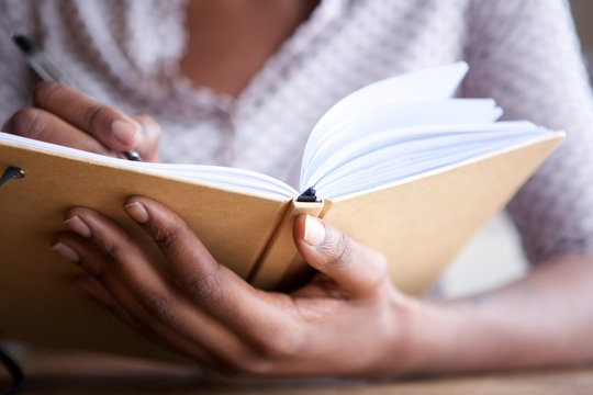 Close up female hands holding pen and book