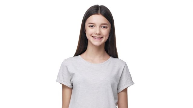 Portrait of cheerful student girl looking at camera with smile and gesturing on camera with ok sign, isolated over white background. Concept of emotions
