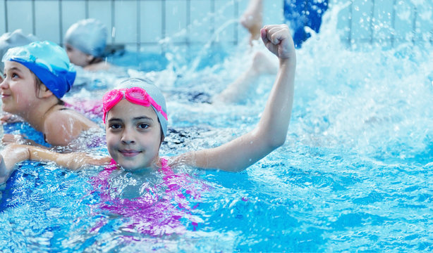 Happy children kids group at swimming pool class learning to swim