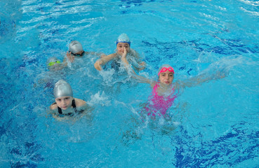 Obraz na płótnie Canvas Happy children kids group at swimming pool class learning to swim
