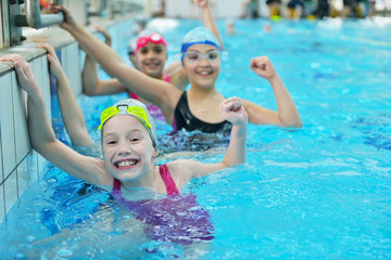 Happy children kids group at swimming pool class learning to swim