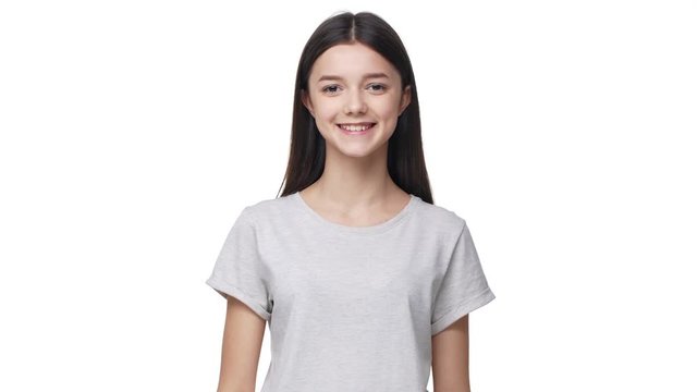 Portrait of lop-eared pleased woman with long dark hair in basic t-shirt laughing like happy girl, isolated over white background in studio. Concept of emotions