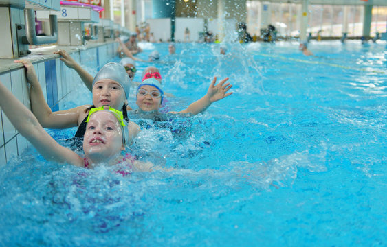 Happy children kids group at swimming pool class learning to swim