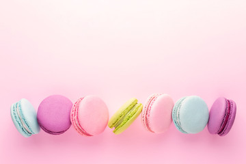 The row of colorful macarons on pink background. Top view with place for text.