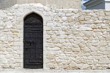 Stone white wall with dark metal door of the Muslim Islamic Mosque. Ramadan Kareem background.