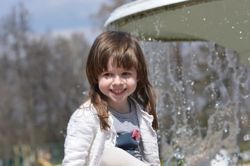 Adorable little girl's portrait by the fountain
