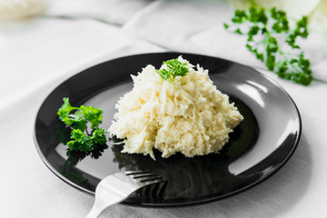 Cabbage salad with a sprig of parsley on a black plate on a white table