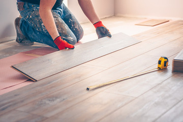 Worker professionally installs floor boards - obrazy, fototapety, plakaty