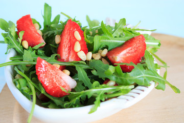 Rocket salad with strawberries and pine nuts. Close-up. Copy space.