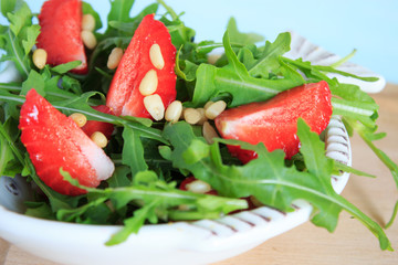 Rocket salad with strawberries and pine nuts. Close-up.