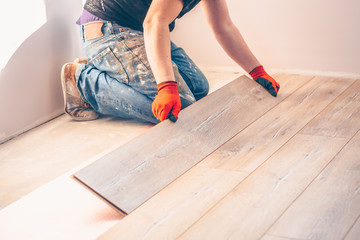 Professional installation of floor covering, the worker quickly and qualitatively mounts a laminate...