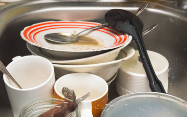 Dirty unwashed kitchen utensils and dishes in the sink