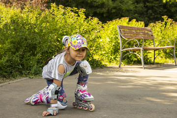 Cute little girl rollerblading in good weather in the park