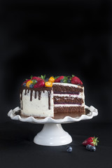 Homemade chocolate birthday cake with berry jelly, ceam cheese, chocolate decorations and berries