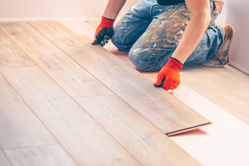 Professional installation of floor covering, the worker quickly and qualitatively mounts a laminate...