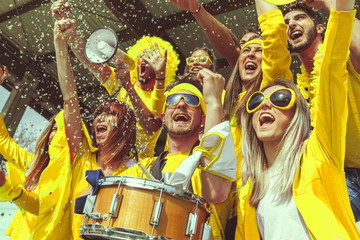 group of fans dressed in yellow color watching a sports event