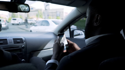Afro-American businessman going to meeting, looking through questions on phone