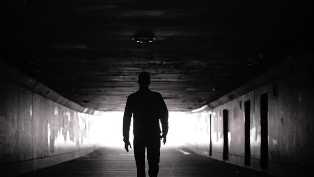 Dark man silhouette. Person walking in tunnel. Concept depression
