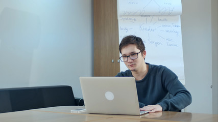 Young man video conferencing with tutor on laptop in class room