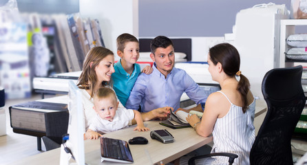 Happy family choosing material for mattress with saleswoman