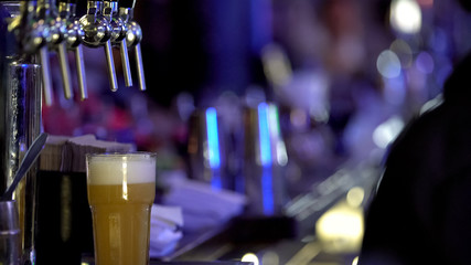 Big glass of fresh cold beer with frothy white foam waiting for man ordered it