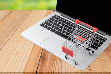 Small shopping cart, Trolley on Laptop for shopping online with copyspace nature background, Technology online marketing and business trading concept