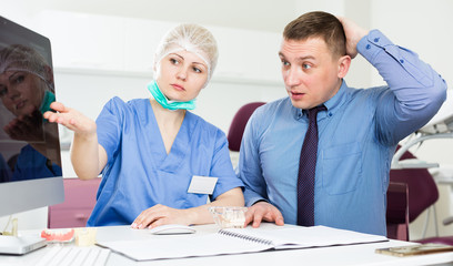 Obraz premium Female dentist explaining diacrisis to shocked man
